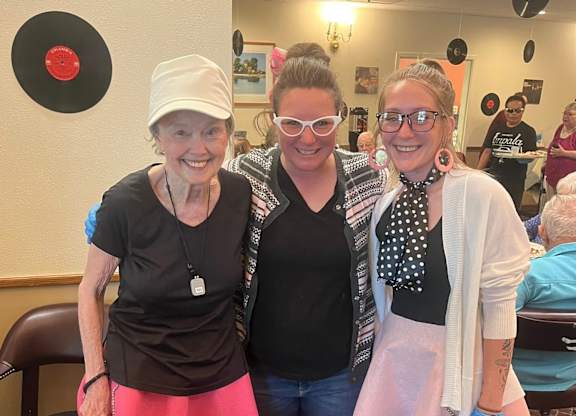 Three women wearing pink skirts at River Commons Senior Living, California