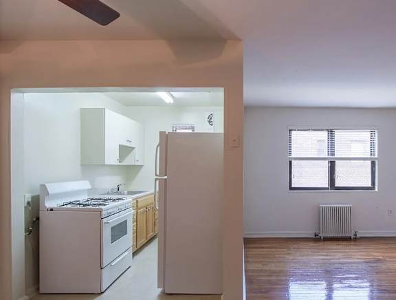 A kitchen with white appliances and wooden floors.