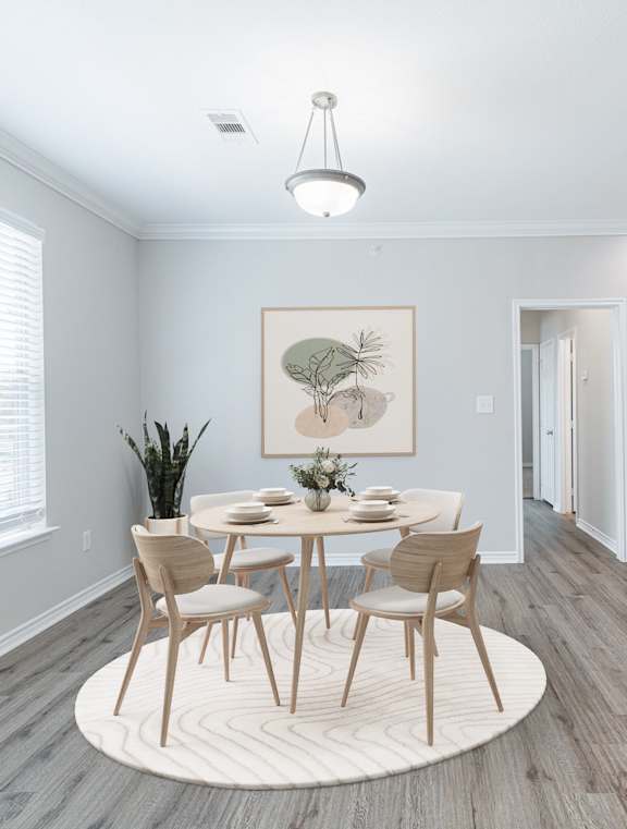 A dining room with a table set for four and a kitchen in the background.