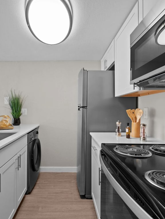 a kitchen with stainless steel appliances and white cabinets at Tides on McDowell, Phoenix, AZ
