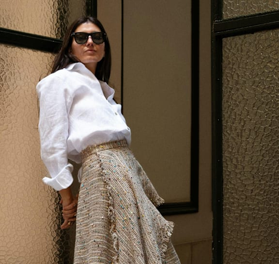 A woman wearing a white shirt and a patterned skirt.