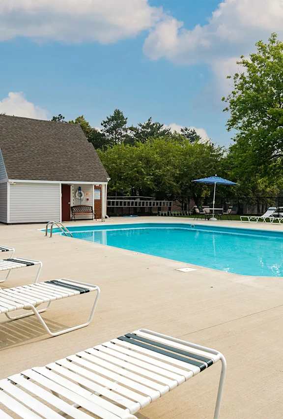 A pool with sun loungers and a building in the background.