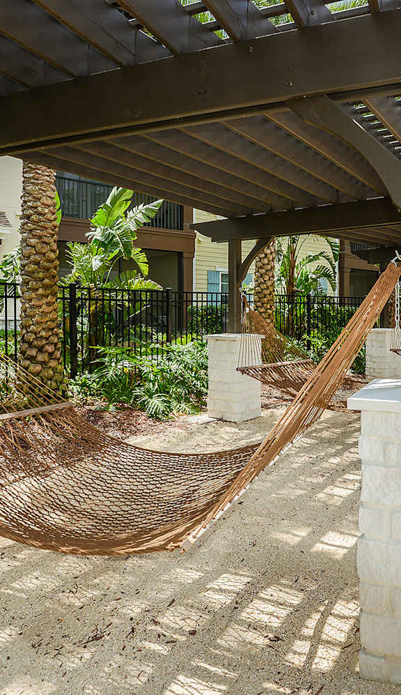 A hammock is strung between two wooden posts on a patio.