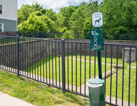 a black wrought iron fence with a green sign on it and a yard behind it