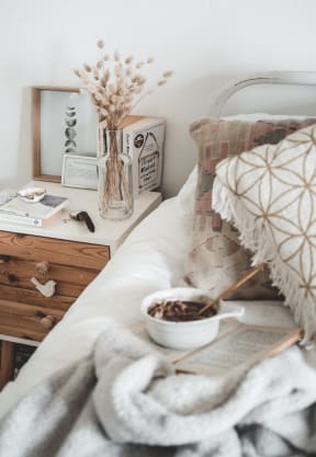 A bedroom featuring a bed, a bedside table, and a vase of flowers for decoration.