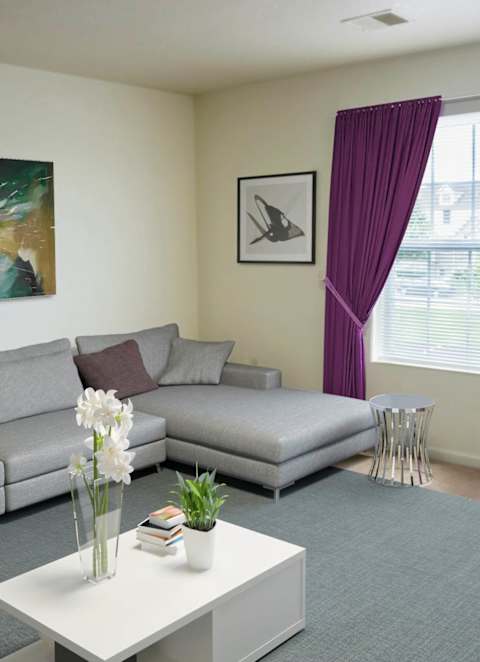 A living room with a grey sofa, a white coffee table, and a painting on the wall.