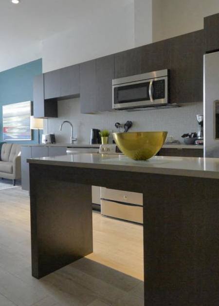 A modern kitchen with a stainless steel refrigerator and wooden flooring.