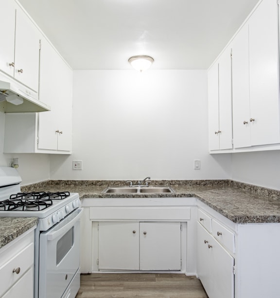 an empty kitchen with white cabinets and granite counter tops