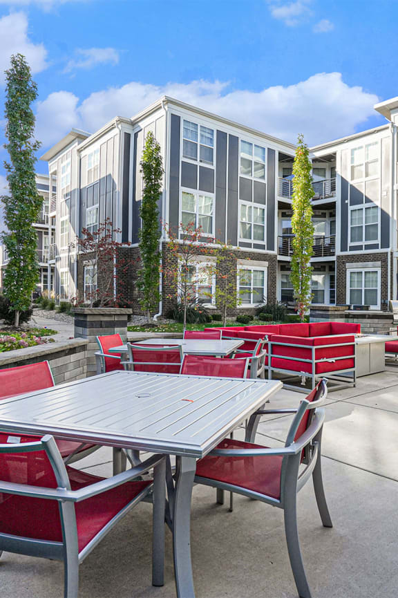 an outdoor patio with tables and chairs in front of an apartment building