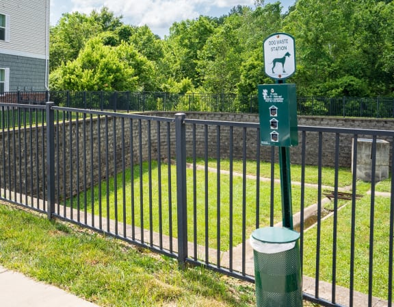 a black wrought iron fence with a green sign on it and a yard behind it