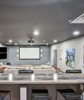 a movie theatre style room with a large tv and chairs at the vue apartments in indianapolis 