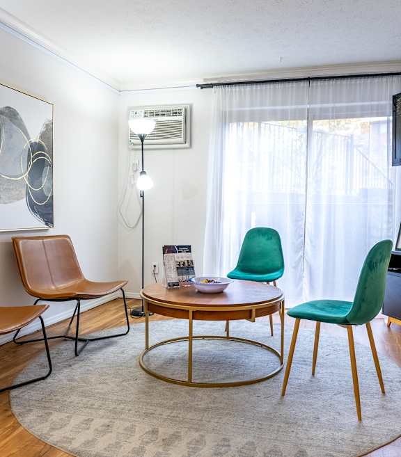 A living room with a brown leather chair, a green chair, and a wooden coffee table.
