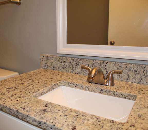 A bathroom with a granite countertop and framed mirror at The Avery at Auburn Apartments in Auburn, AL
