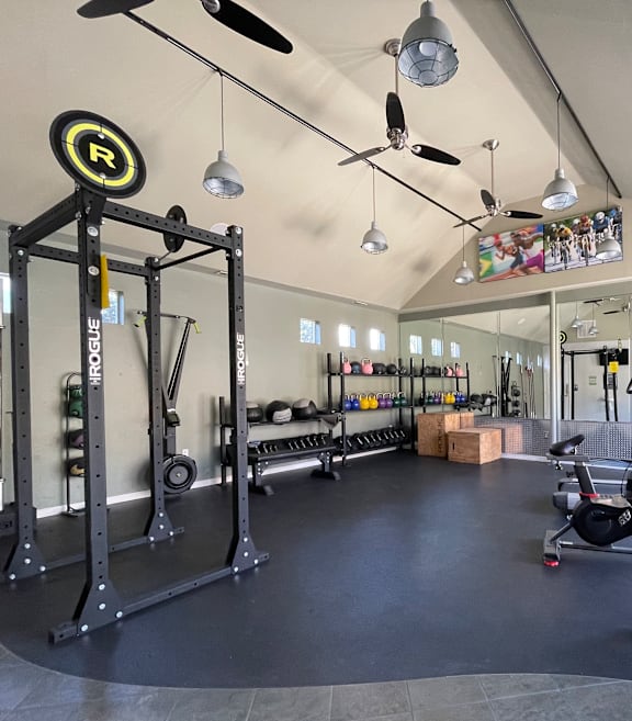 A gym with a variety of equipment including a weight rack and a barbell.