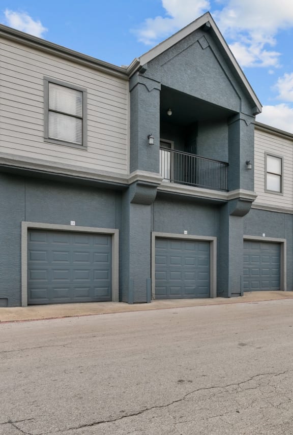 a gray house with garages and a street in front of it  at 5636 Apartment Homes, Texas, 75254