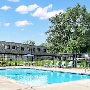 A pool area with sun loungers and a building in the background.
