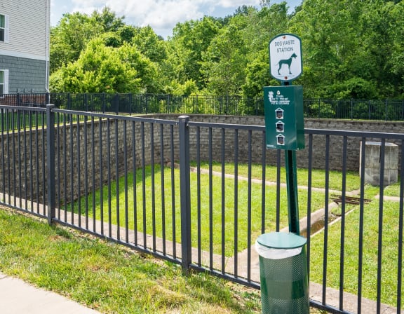 a black wrought iron fence with a green sign on it and a yard behind it