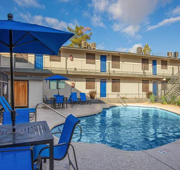 A pool area with blue chairs and a table.