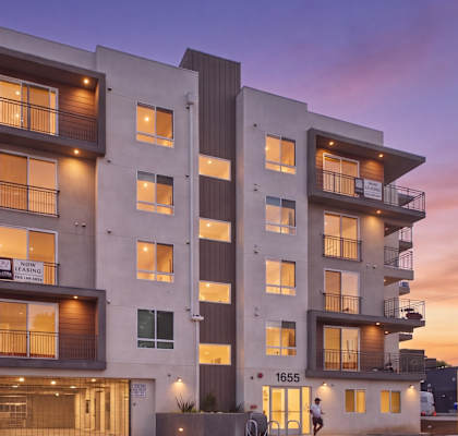 A modern apartment building with balconies and multiple windows.