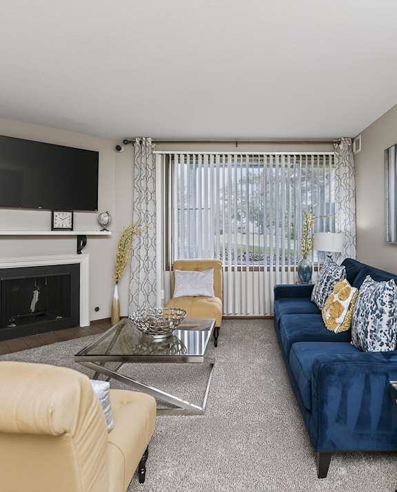 A living room with a blue couch and a fireplace.