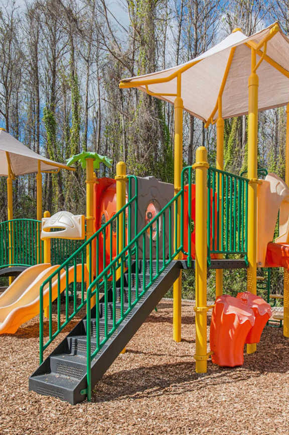 A playground with a green slide and orange and yellow slides.