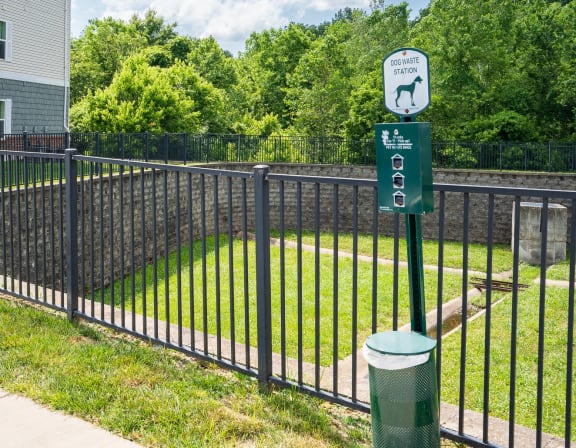 a black wrought iron fence with a green sign on it and a yard behind it