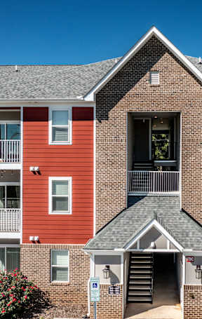 A red and grey apartment building with a blue sky in the background.