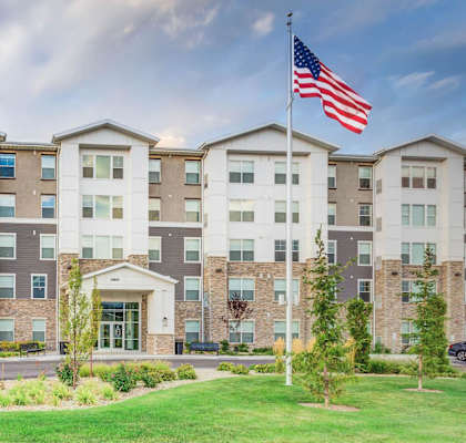 A large building with a flag on top and cars parked in front.