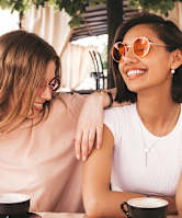 Two women sitting at a table with cups of coffee.