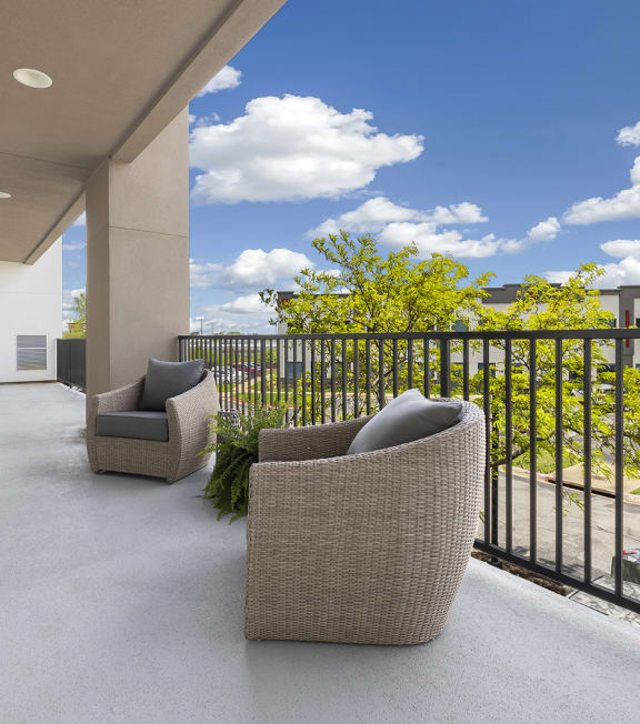 a large balcony with two chairs and a view of the street