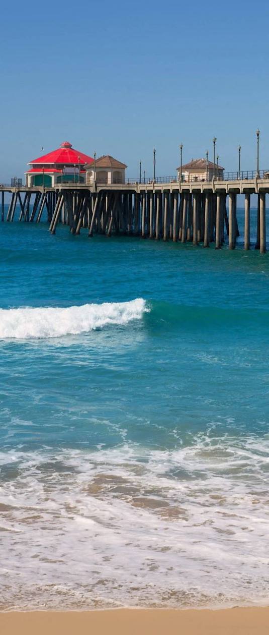 a pier with a beach and the ocean next to it