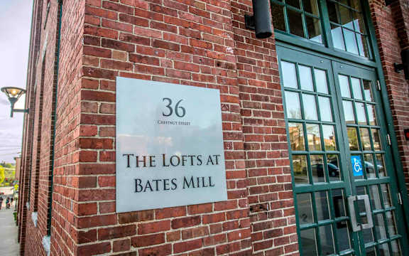 A sign on a brick wall that says "36 The Lofts at Bates Mill.".