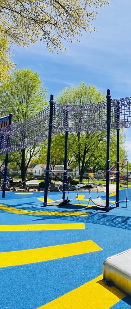 A playground with a slide and climbing net.