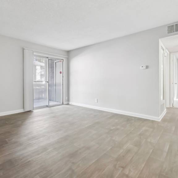 Living room with vinyl wood flooring and a sliding door in the B1 floor plan at Riverwood Crossing apartments in Roswell, GA..