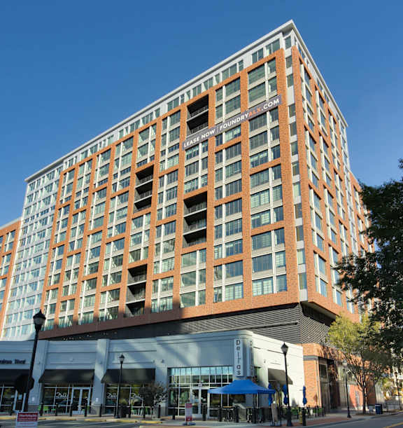 A tall building with a curved glass entrance sits on a street corner.