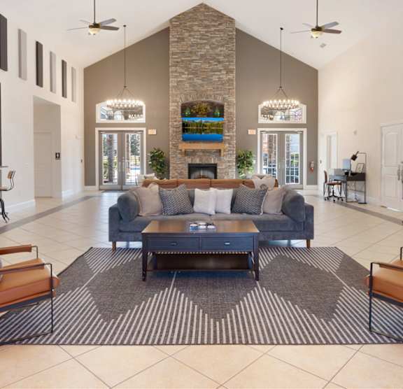 A modern living room with a stone fireplace and a large rug. at Stone Gate Apartments, Spring Lake, 28390