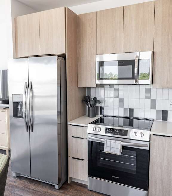 A modern kitchen with a stainless steel refrigerator, oven, and microwave at Anthem House Apartment, Huntsville, AL, 35806