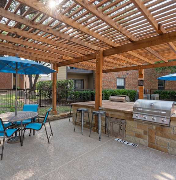 A BBQ grill is in the foreground of a residential area with palm trees.