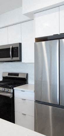 A modern kitchen with a stainless steel refrigerator and black stove top oven.