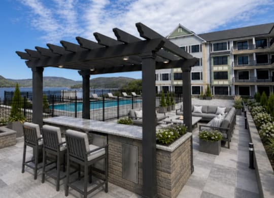 Outdoor dining area with pergola and waterfront views at East Point on Hudson Apartments, New York