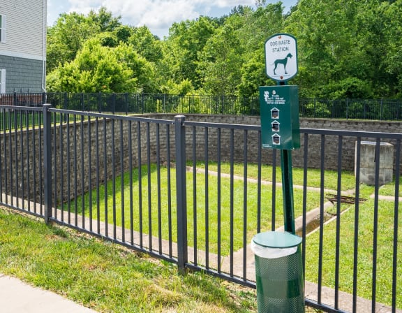 a black wrought iron fence with a green sign on it and a yard behind it