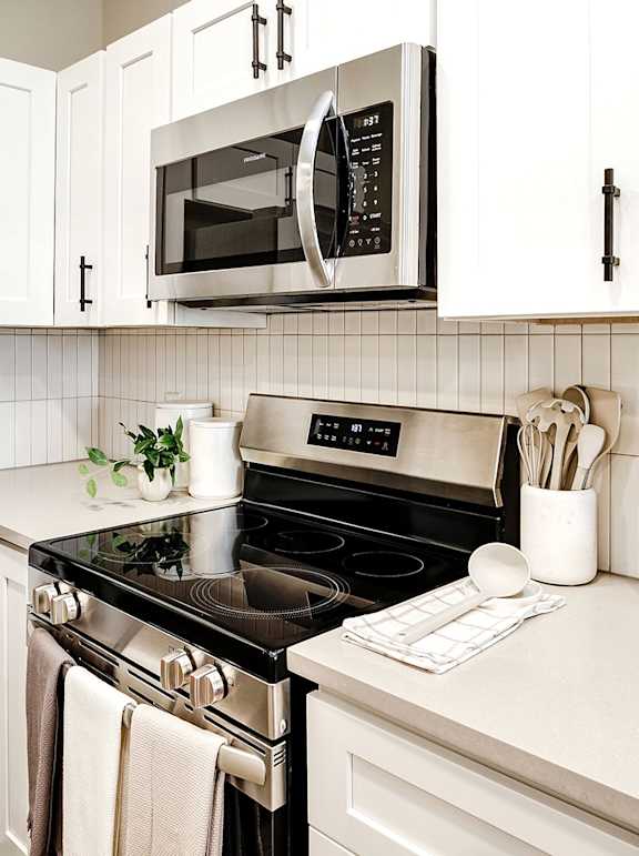 A modern kitchen with white cabinets and stainless steel appliances.