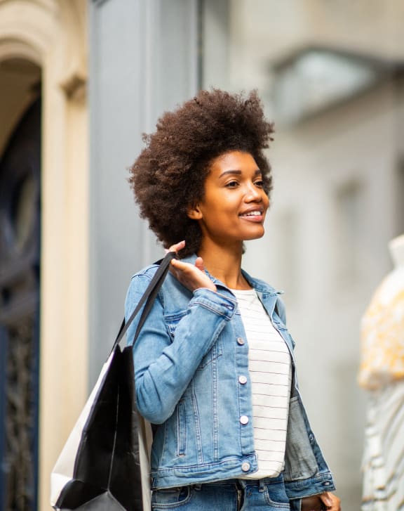 woman standing in front of a store window holding a bag