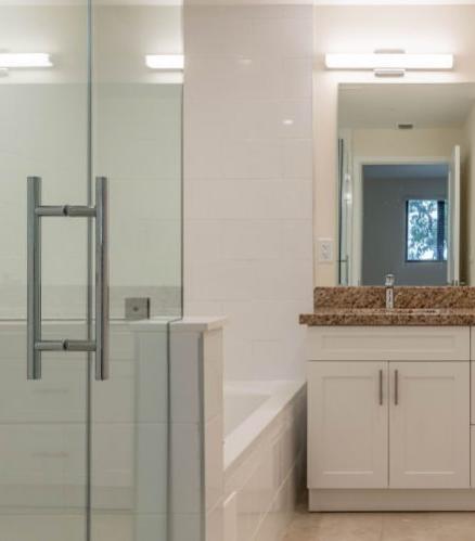 A bathroom with a glass shower door and a granite countertop.