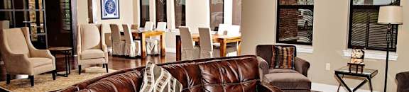 A brown leather couch in a living room with a wooden table in front of it.