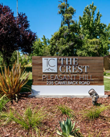 a sign in front of a house with trees in the background