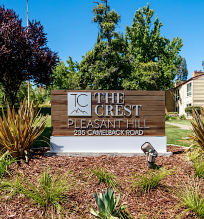 a sign in front of a house with trees in the background