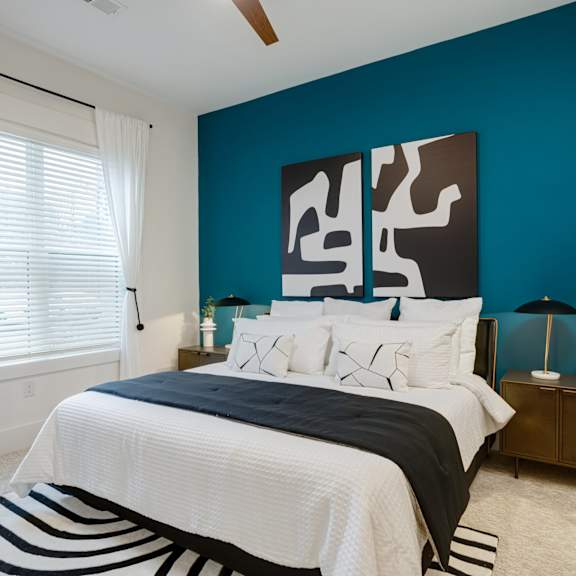 A bedroom with a bed, nightstand, and a large abstract painting on the wall. at Vintage Edge Nashville Apartments, Tennessee, 37211