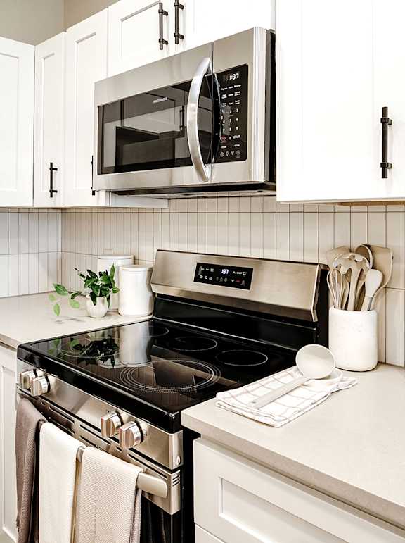 A kitchen with white cabinets and a black stove top.