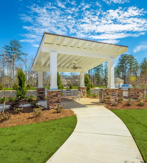 A white covered walkway leads to a building with a stone pillar on each side.